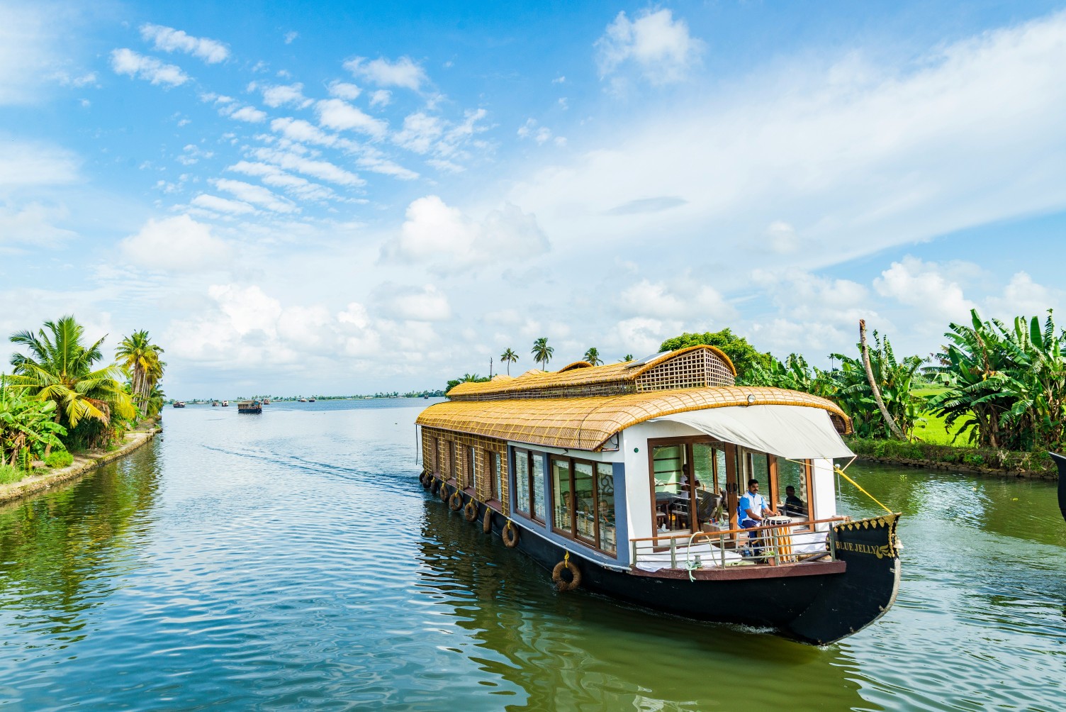 A traditional houseboat gliding through Alleppey's backwaters at sunset.