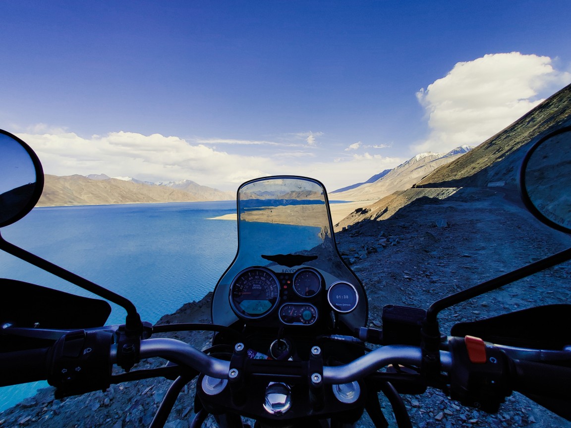  Enfield bike cruising along a high-altitude pass in Ladakh, capturing the essence of a classic Himalayan road trip.