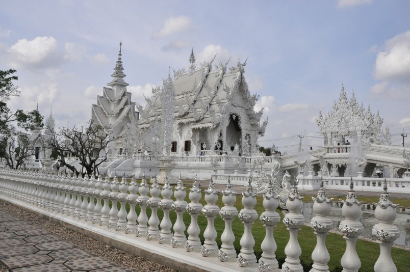 The White Temple (Wat Rong Khun) in Chiang Rai, Thailand, with intricate white carvings and reflective surfaces under a clear sky.