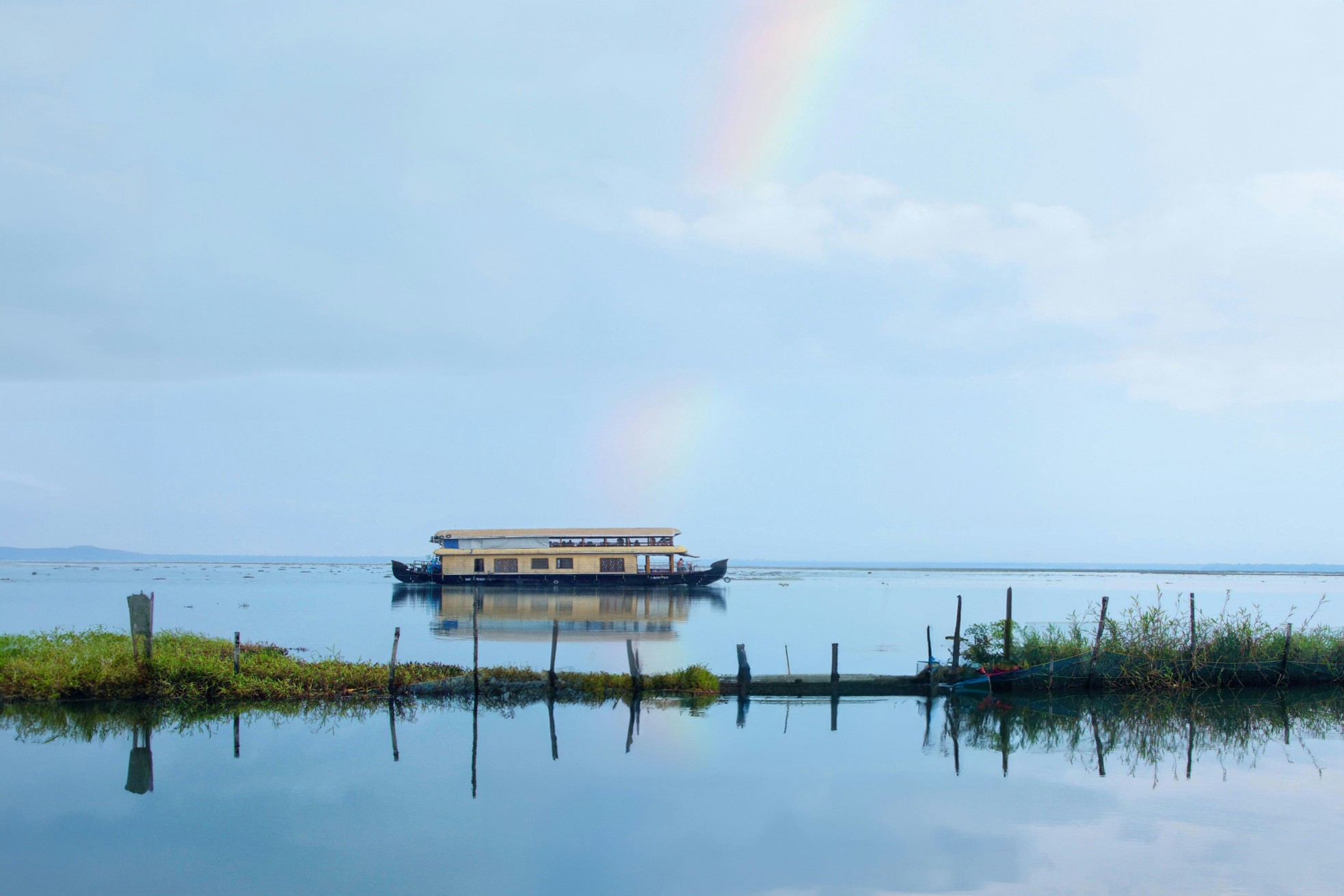 Traditional houseboat on  Kumarakom, Kerala backwaters with a rainbow in the sky.