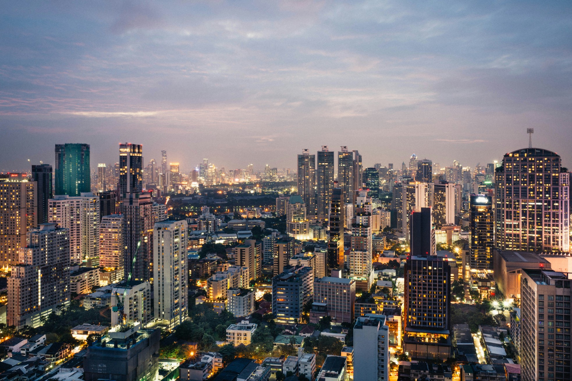 Bangkok city skyline at dusk with illuminated skyscrapers.