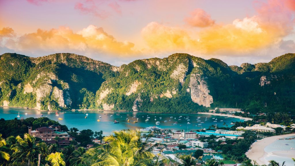 Scenic view of Phi Phi Island with turquoise waters, limestone cliffs, and boats anchored along the coast.