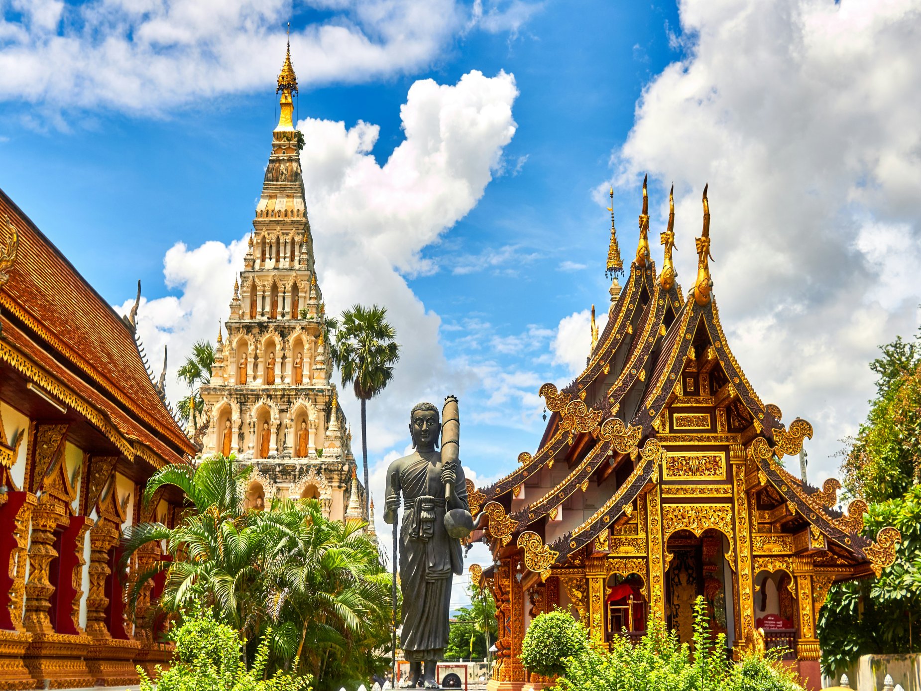 Ornate golden temples and a tall Buddha statue at Wat Phra That Lampang Luang in Thailand
