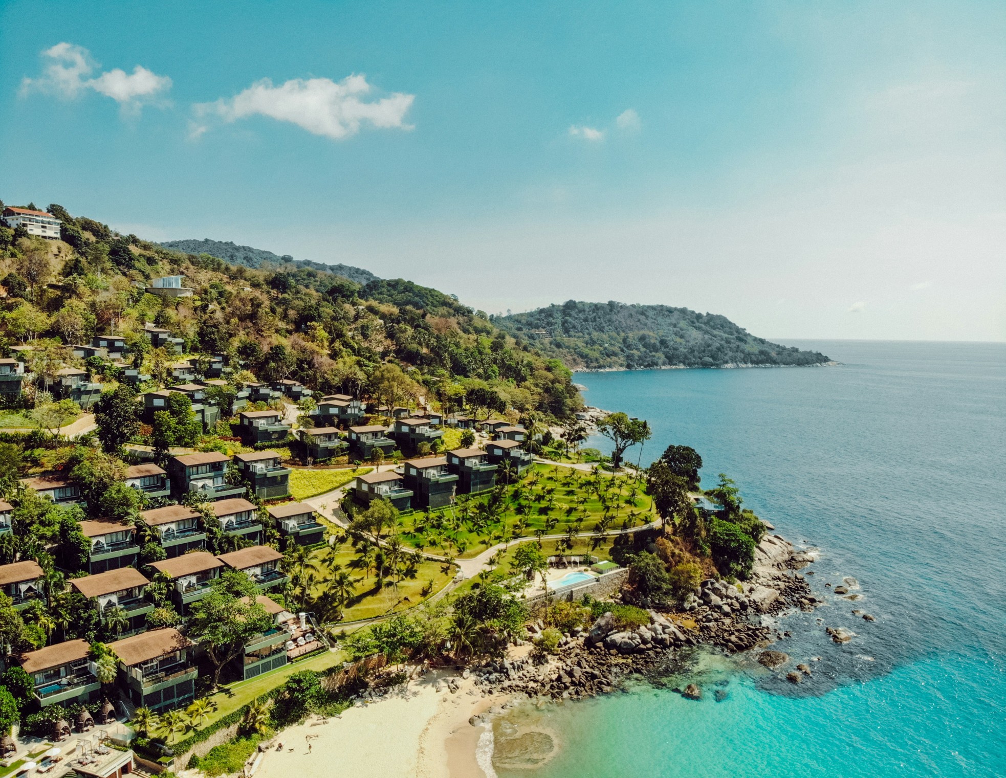 Luxury seaside villas on a tropical hillside overlooking turquoise waters in Phuket.