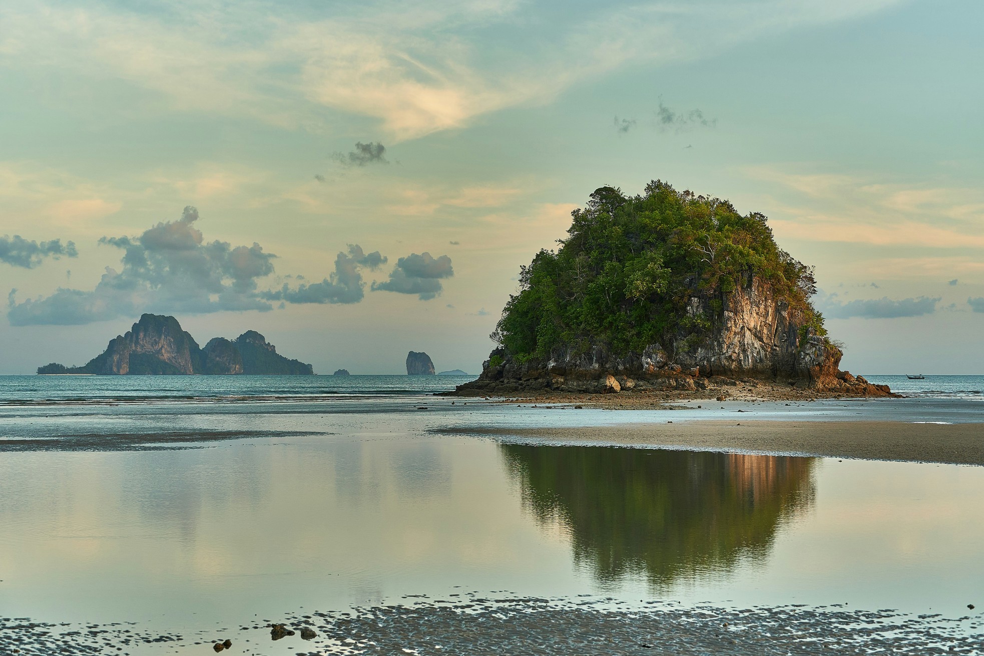 Scenic view of Ao Nang, Thailand with calm sea, island cliffs, and sunset reflection.