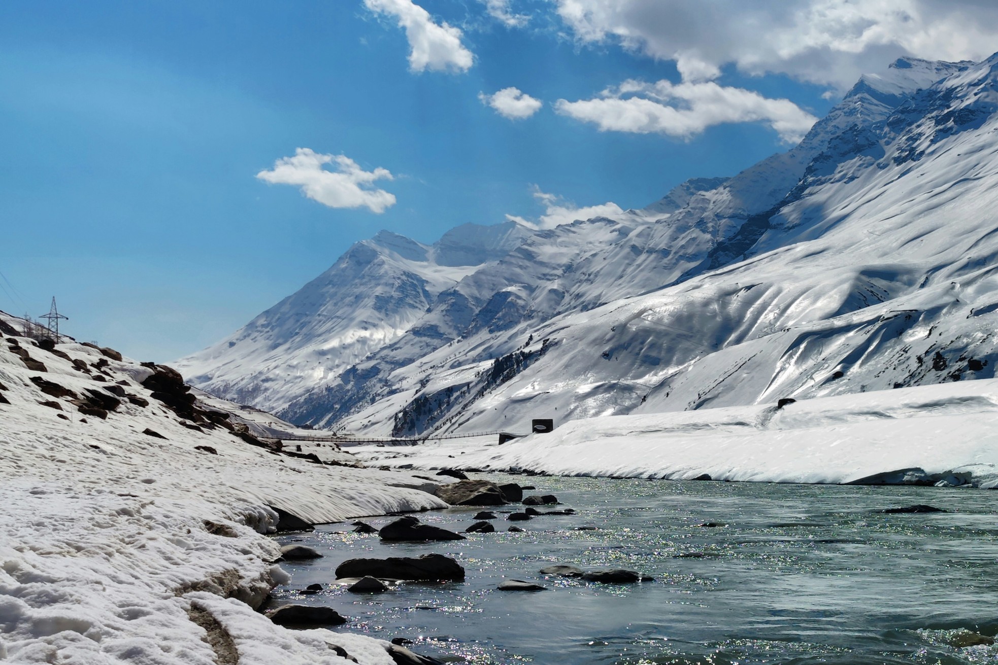 Snow-covered peaks and winding road at Rohtang Pass in Himachal Pradesh.