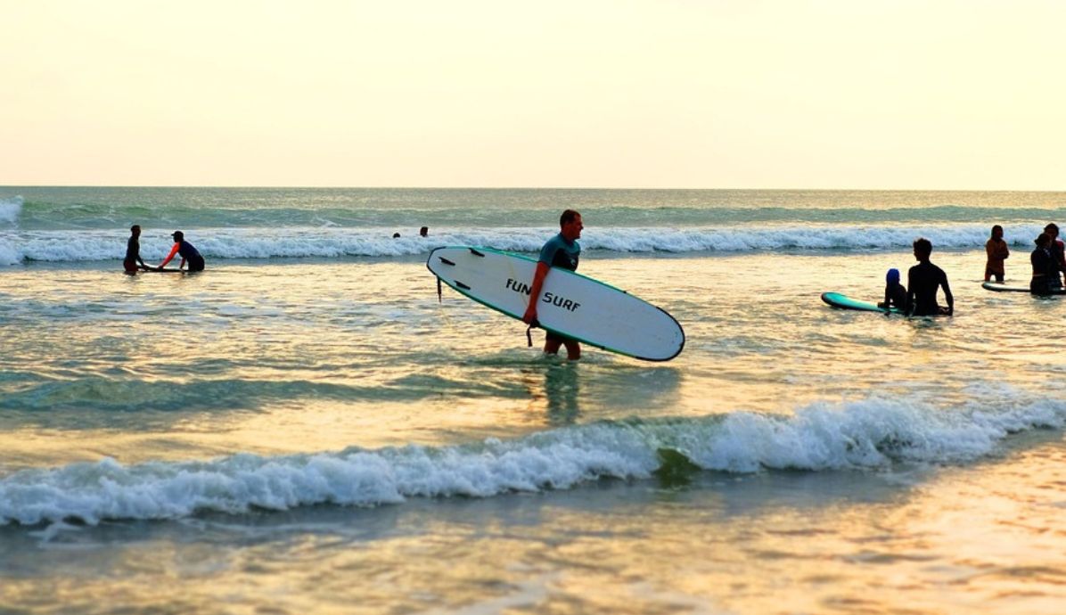 Travelers with surfboards enjoying a stunning Bali beach sunset, perfect for surfing and romantic getaways.