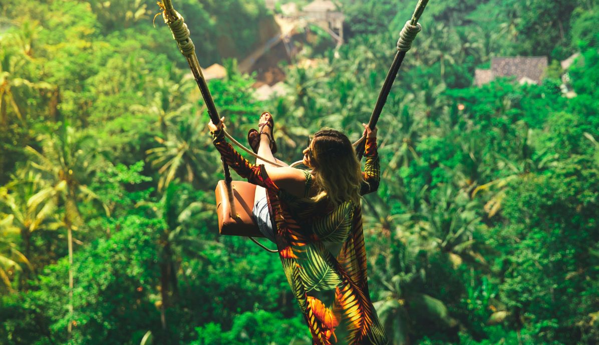 Traveler on the famous Bali swing overlooking lush jungle, a popular spot for adventure and honeymoon photos.