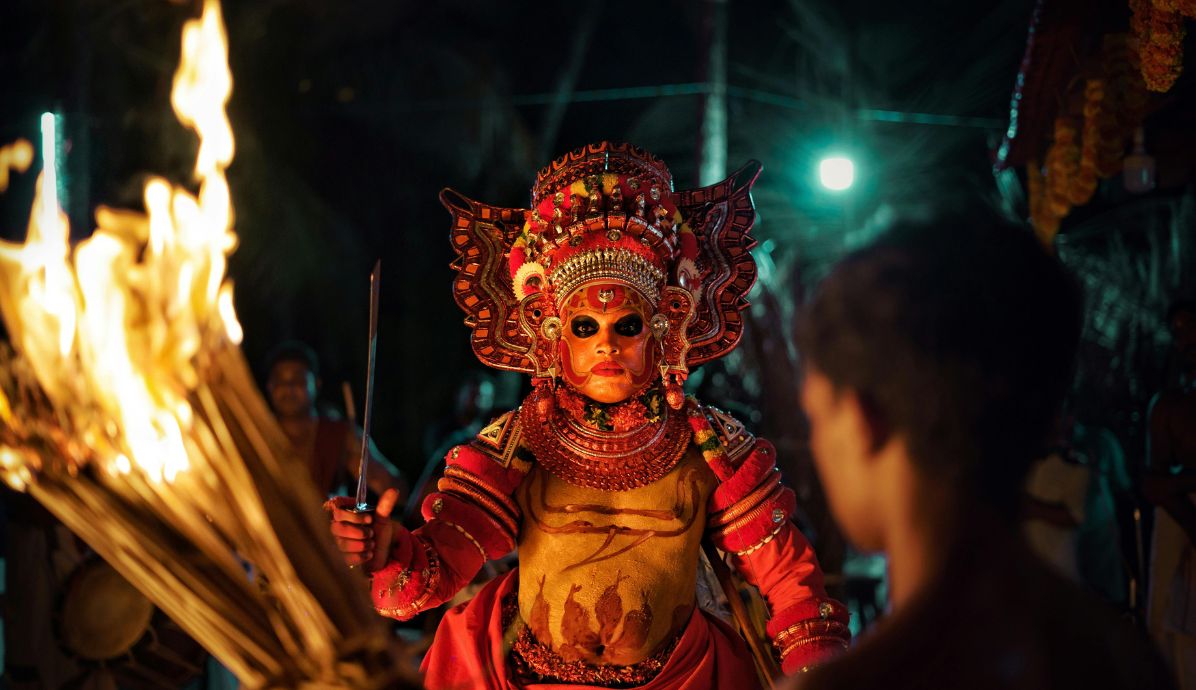Theyyam performance in Kerala with vibrant costumes and fire ritual, highlighting cultural experiences for volunteers.