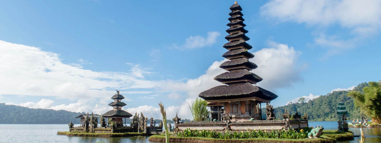 Ulun Danu Beratan Temple on Lake Beratan in Bali, Indonesia surrounded by water and mountains under a bright sky