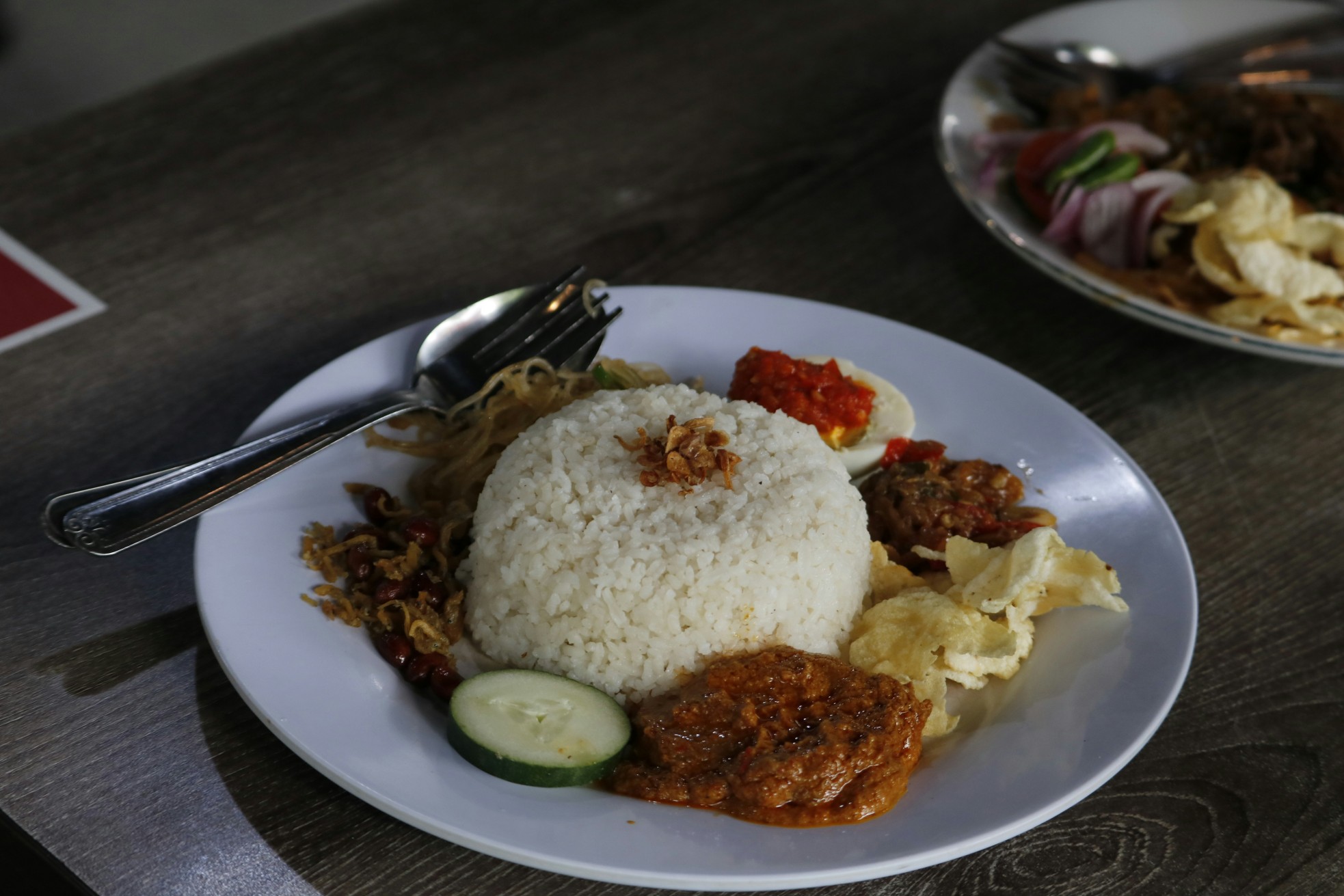 Nasi lemak, a traditional Malay curry paste rice dish served on a white plate. 