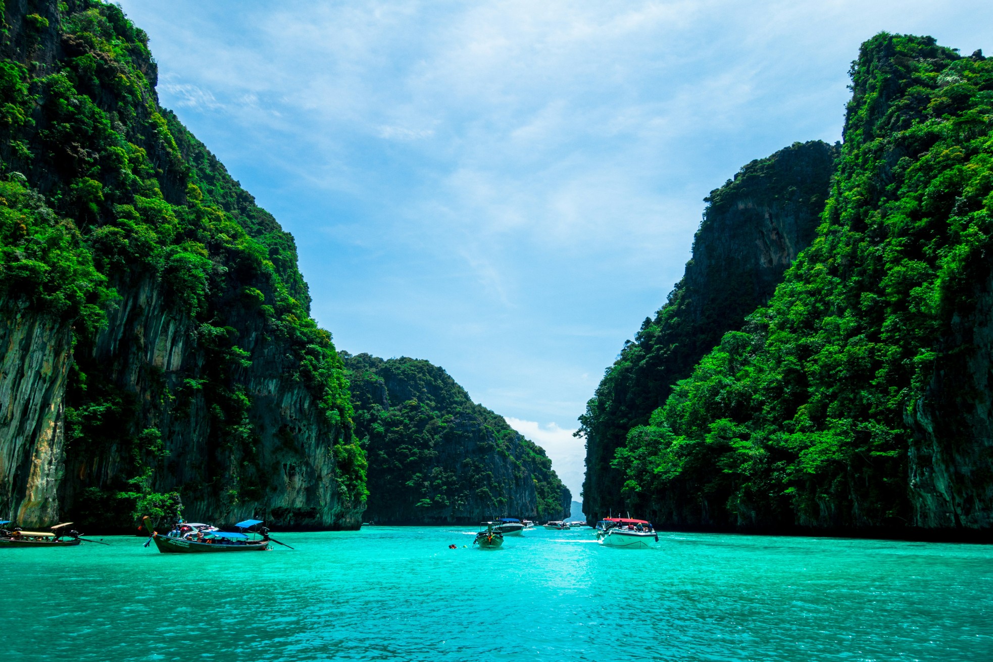 Boats on turquoise water with limestone cliffs in Thailand, a scenic workation spot.